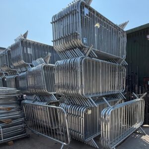 Bulk stack of galvanised steel crowd control barriers for creating safe pedestrian walkways and event perimeters.