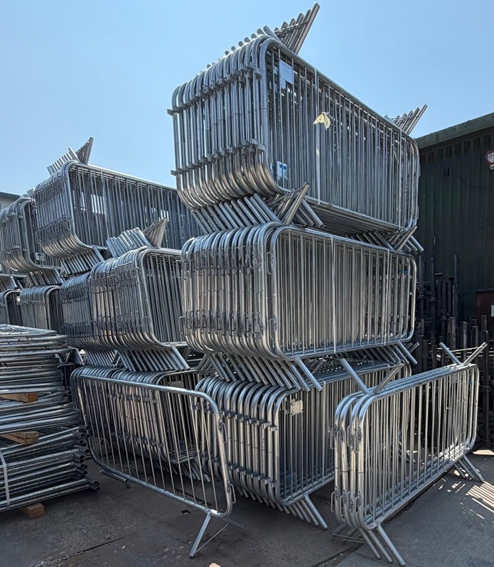 Bulk stack of galvanised steel crowd control barriers for creating safe pedestrian walkways and event perimeters.