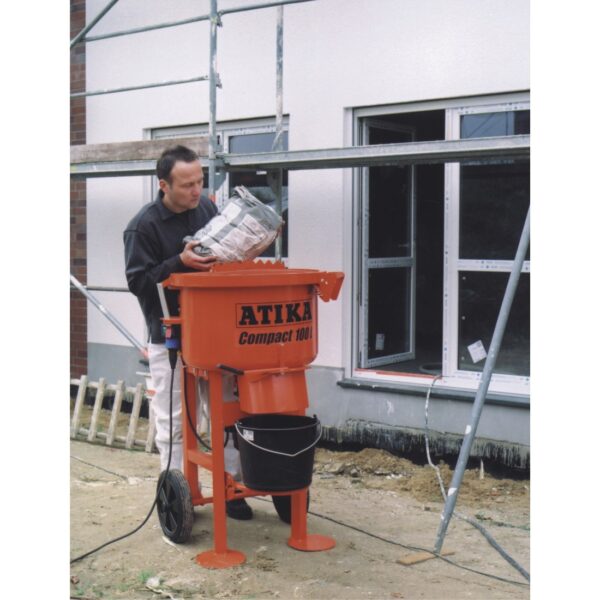 Atika Compact 100 pan mixer in use on site with a plasterer pouring a bagged mix into the mixing drum.